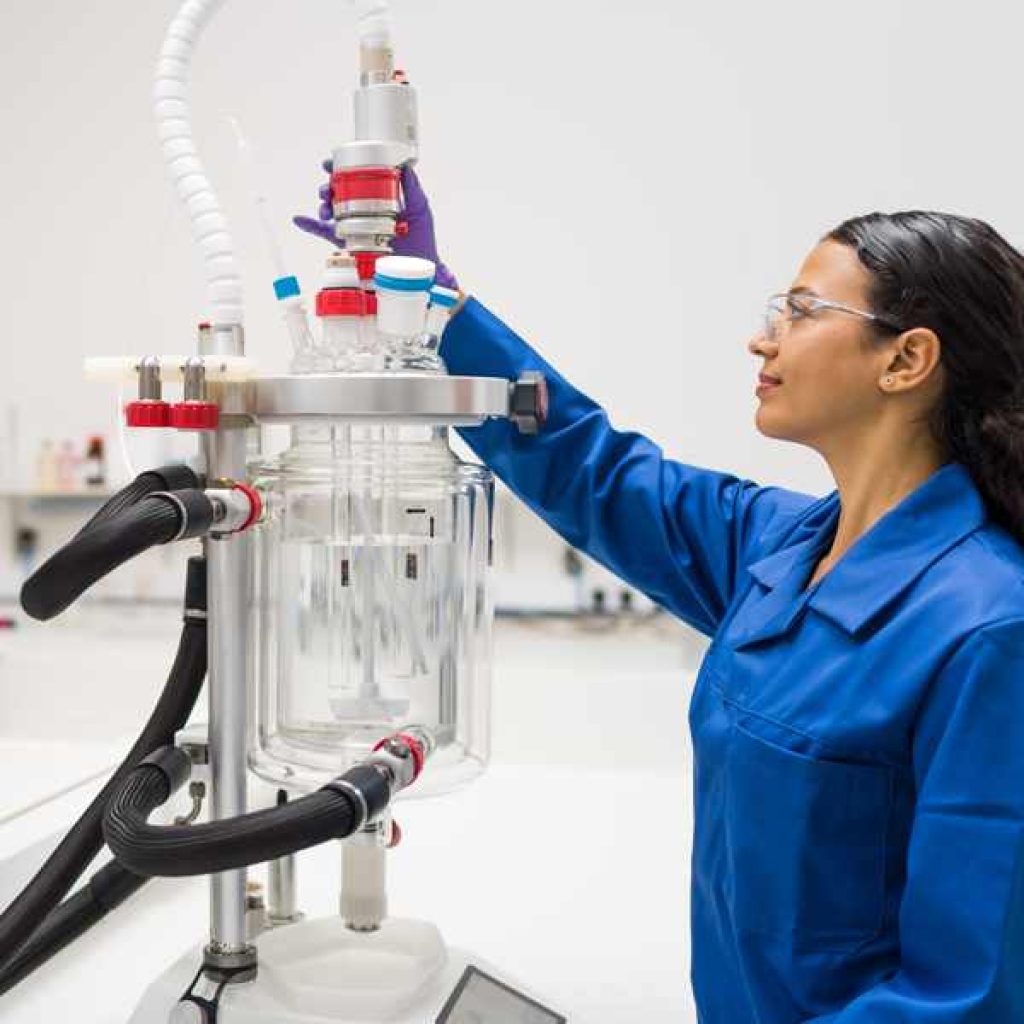 Woman scientist in the blue lab coat testing jacketed reactor in the lab